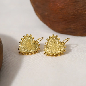 Macro shot of 18k gold plated heart hoop earrings with detailed beaded texture finish