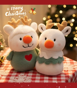 Close-up of adorable plush deer toys in festive sweaters on a red checkered background