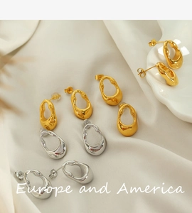Macro shot of gold and silver irregular geometric earrings on elegant satin fabric