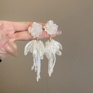 Detail of elegant cream floral tassel earrings with beaded fringe held in hand
