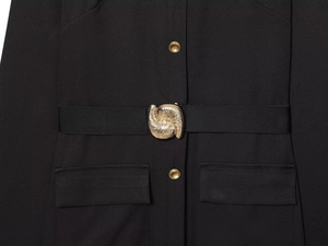 Détail de la robe midi noire montrant la boucle martelée dorée et les boutons