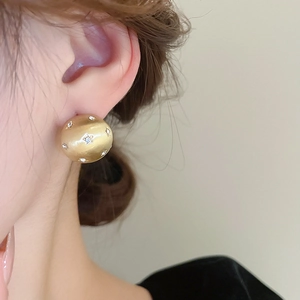 Close-up of a brushed gold star earring with rhinestones worn by a model