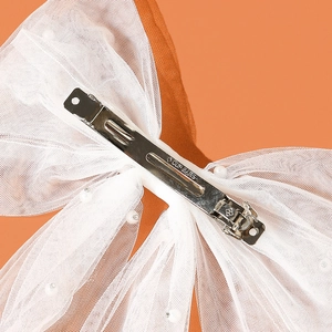 Macro view of white mesh bow hair clip with faux pearls and metal alligator clip detail