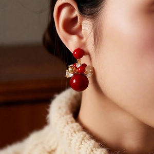 Detailed close-up of 18K gold plated red bead earrings with crystal on model