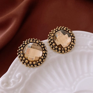 Macro detail of retro gold-tone round stud earrings with amber resin and beaded edges