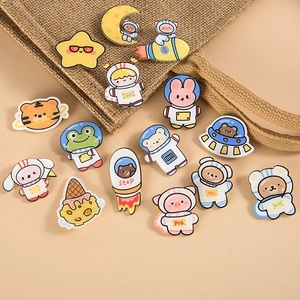 Cute cartoon astronaut and animal enamel pins set displayed on a stylish fabric bag