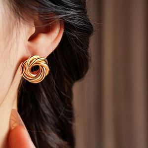Close-up of golden geometric interlaced knot earring worn on a model's earlobe