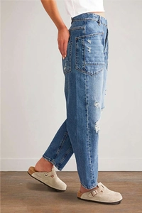 Détail latéral d'un jean vintage délavé avec ourlets effilochés et coupe ample tendance