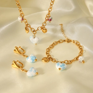 Détails de parure de bijoux dorés avec pendentifs cœur aux motifs floraux et nuages