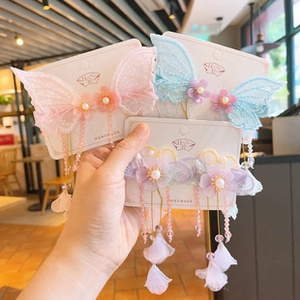 Detail view of handmade butterfly hair clips with floral pearls and long tassels