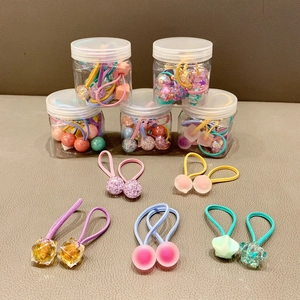 Macro detail of colorful kids' elastic hair ties with star and geometric charms in jars