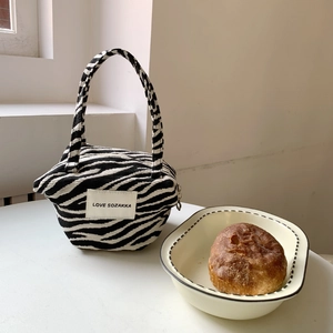 Detail of zebra pattern fabric handbag with LOVE label on white table setup