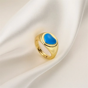 Detailed view of golden heart ring with blue zircon inlay on white silk background