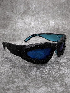 Detailed close-up of avant-garde sunglasses with organic 3D texture and blue lenses