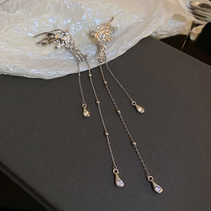 Dettaglio di orecchini a farfalla argentati con lunghe catene a nappa e strass brillanti