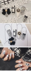 Macro detail of black and white tweed press-on nails with 3D camellia and bow charms