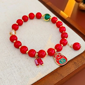 Détail macro du bracelet à billes rouges avec breloque Maneki-neko dorée et accents cristal