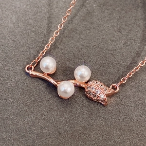 Detail of rose gold vine necklace featuring white pearls and zircon encrusted leaves