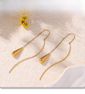 Macro shot of gold-plated stainless steel teardrop pendant earrings with long chain tassels