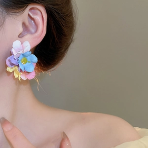 Detailed view of colorful chiffon flower earrings worn on model for a sweet summer style