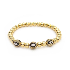 Detail view of 18K gold beaded bracelet with crystal-encrusted evil eye charms