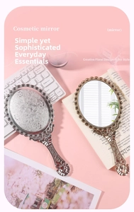 Close-up of vintage handheld makeup mirror featuring floral embossed back and wavy edges