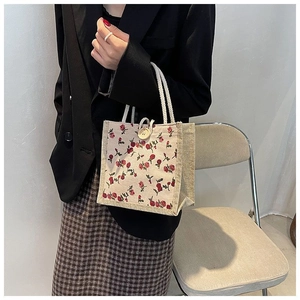 Detail of floral mini tote bag with red roses print and wooden button closure