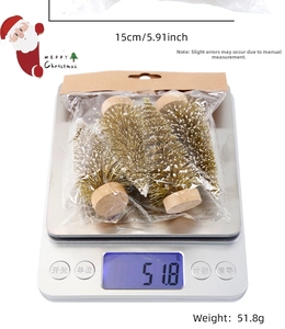 Mini gold Christmas trees with faux snow in retail packaging on a digital scale