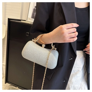 Close-up of sparkling silver sequin evening bag with gold circular handle and metal chain