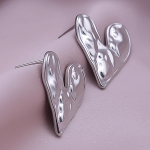 Macro shot of silver heart studs with textured hammered finish and liquid metal effect
