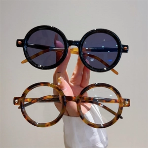 Détails de lunettes de soleil rondes rétro portées à la main en noir et écaille