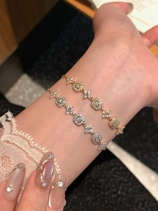 Macro detail of 18K gold and silver plated bracelets with square zircon flower links