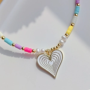Macro detail of dopamine-colored heishi bead necklace with a white heart pendant