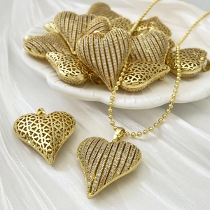 Detail of gold heart pendant with striped zircon inlay and hollow back on silk texture