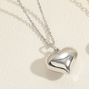 Macro view of polished silver-colored 3D heart pendant necklace with smooth mirror finish