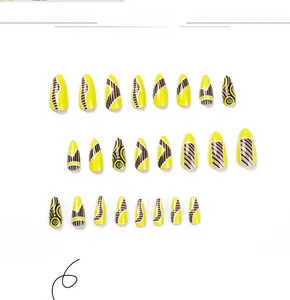 Detail of 24 yellow press-on nails with abstract black and brown geometric swirl lines