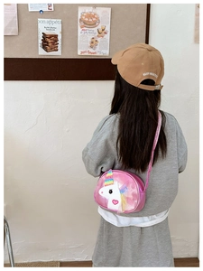 Girl wearing a pink unicorn crossbody bag with rainbow decorations and heart detail