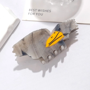 Detail of eagle-shaped hair claw clip in grey marble acetate with yellow beak accent