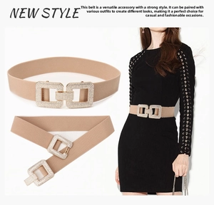 Detail of beige elastic waist belt featuring a square rhinestone buckle on a black dress
