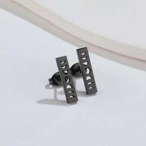 Macro detail of matte black rectangular earrings with moon phase cutout patterns