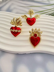 Detailed view of red enamel sacred heart jewelry with golden wings and zircon accents