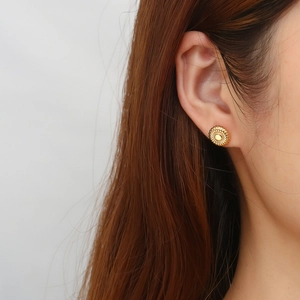 Close-up of gold flower stud earrings with radial texture on female model's ear