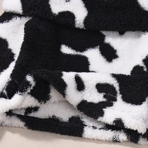Macro detail of soft black and white cow print plush fabric with rich fuzzy texture