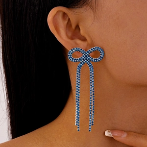 Détail de boucles d'oreilles à nœud papillon en strass bleus portées par un mannequin de profil