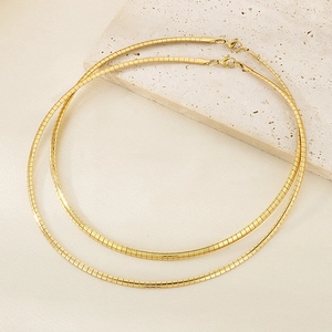 Detail of minimalist 18K gold plated herringbone snake chains on decorative stone background