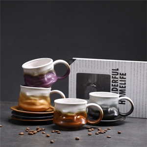 Macro detail of four assorted handmade ceramic coffee cups with gradient glazes and saucers