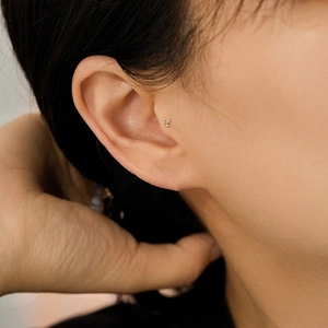 Close-up of three small sparkling diamonds on an S925 silver stud earring worn on the ear