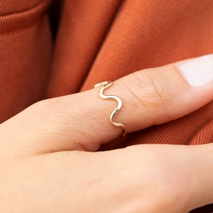 Detail shot of wavy gold S925 sterling silver ring worn on finger with smooth finish