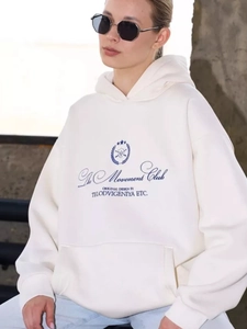 Detailed view of cream hoodie featuring navy blue letter print and kangaroo pocket detail