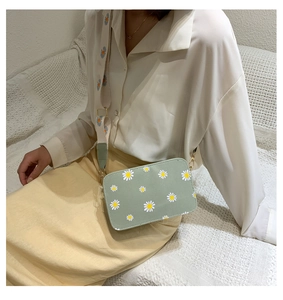 Detail of mint green crossbody bag with daisy prints and wide patterned shoulder strap